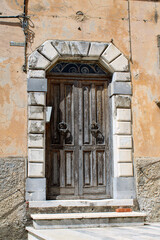 Fototapeta na wymiar Portale con bugnato ad arco e porta ammalorata in legno