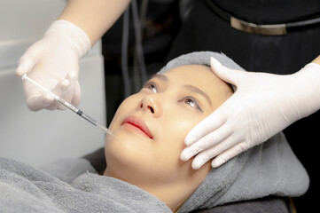 Experts perform injections for chin augmentation and anti-aging facials on young women, beauty...