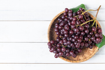 Champagne grapes in bamboo basket and on white wood  background
