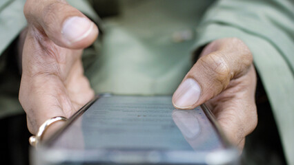 Close up shot of male hands using a cell phone and scrolling through on the touchscreen