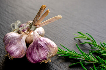 Garlic and rosemary lie on a black background. Spices for cooking