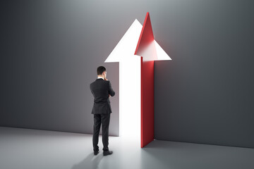 Back view of thoughtful businessman standing in interior with open arrow door. Success, business and opportunity concept.