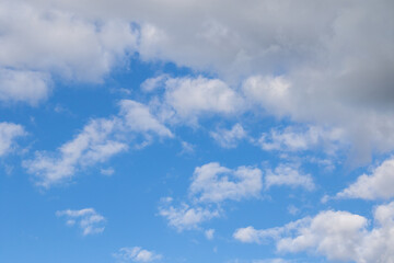 Obraz premium Mehrere weisse Cumulus-Wolken vor strahlen blauem Himmel an einem sonnigen, warmen Tag im Sommer