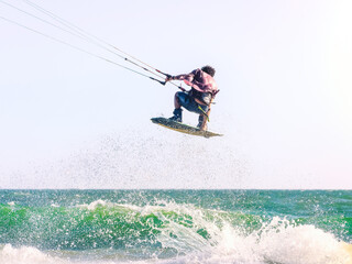 Young man kite boarder jumps over the sea at sunset. Selective focus.