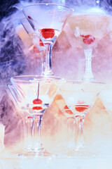 Bright glass pyramid of glasses with cherries, in smoke