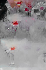 Bright glass pyramid of glasses with cherries, in smoke