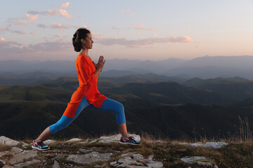 young girl is doing yoga and fitness outdoors in a beautiful mountain landscape. Sunset light, warrior pose