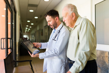 Male doctor showing the x-rays to an elderly retired man at the retirement home