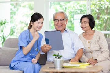 Nursing Home Care concept. Beautiful Asian nurse and elderly person using tablet video call online Chatting with family while in nursing home.