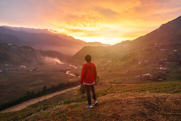 Young man traveler looking at beautiful landscape with mountains and green rice terraces view at...