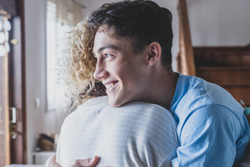 Portrait of middle age mother spend time with teenager son, relatives people hugging at home, adult attentive millennial grateful child wrapped in a plaid or warm sweater loving mommy caring .