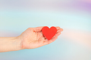 Fototapeta na wymiar red heart in woman's hand on blue abstract background . concept of Valentine's Day, charity, care, love
