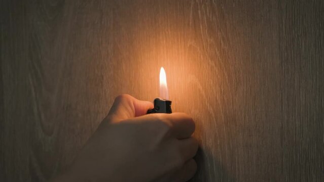 Male hand with a gas lighter. The man makes fire. motion footage. gas lighter video. wooden wall background.
