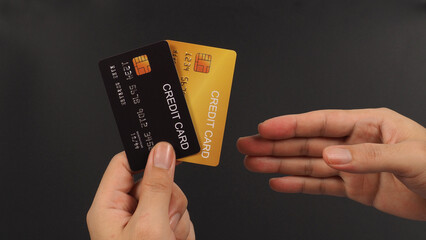 Hand is choosing two Credit Card in black and gold color on black background