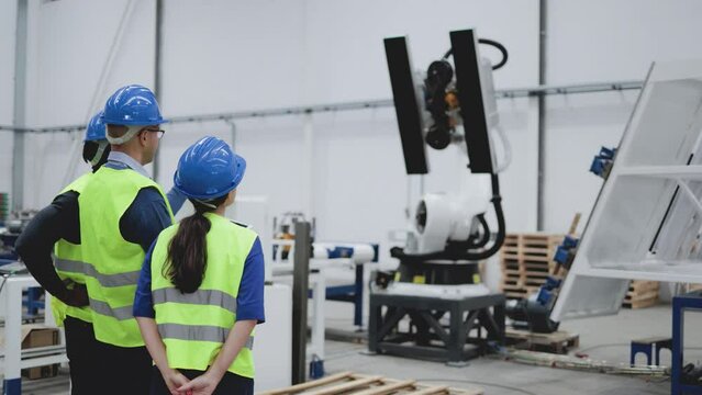 Industrial engineers working with automated arm robot inside AI robotic production factory - New technology concept