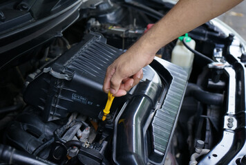 Close up of a man's hand pulling the dipstick to check the oil level.