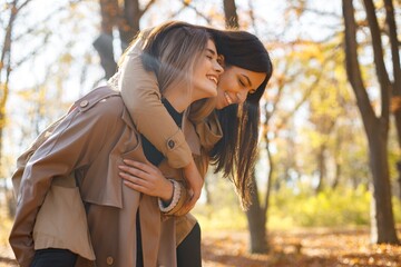 Two girls friends spending time together in autumn park