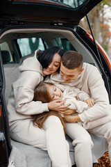 Portrait of a family hugging in a open car's trunk