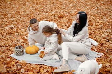 Young family sitting on a blanket in autumn forest