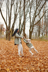 Mother with her daughter playing in autumn forest