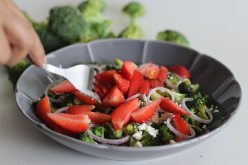 Broccoli with feta cheese and fresh strawberry slices. Sauteed broccoli florets sprinkles with served with crumpled feta cheese and fresh strawberry slices
