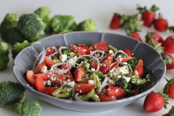 Broccoli with feta cheese and fresh strawberry slices. Sauteed broccoli florets sprinkles with served with crumpled feta cheese and fresh strawberry slices