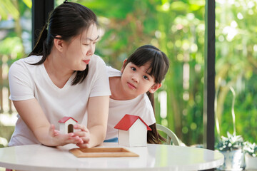 Mortgage and real estate concept of Mother and her little daughter holding their dream house model