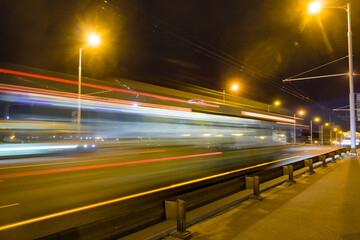 Fototapeta na wymiar A blurred bus moves along the overpass in the evening..