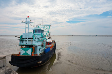Fototapeta premium Boats get stranded during low tide with blue sky and clouds background