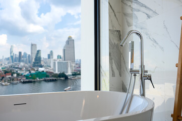 White bathtub near the window, overlooking the cityscape, building landscape outside scenery....