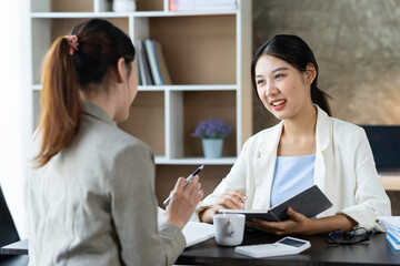 Confident businesswoman discussing the project with colleague close up, diverse employees working together, executive consulting Asian woman client, mentor teaching trainee in the