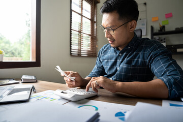 Young asian man calculating expenses household about finance and frustrated on desk at home, male checking bill having stress and worried, debt and tax, expression and emotion, business concept.