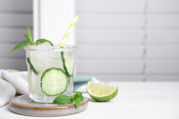 Glass of refreshing cucumber water with mint on white wooden table, space for text