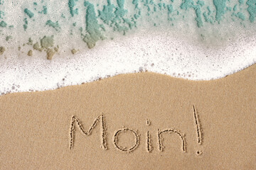 Moin in den Sand geschrieben mit sanfter Meer Welle am  , Strand, Hintergrund