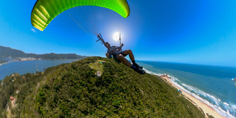Man flying the paragliding over the beach at sunny day