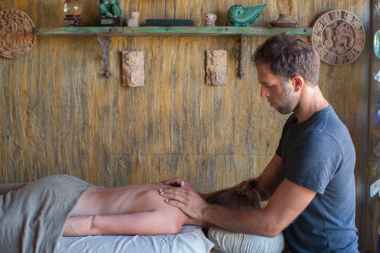 Male Massage Therapist Work On A Female Client In A Peaceful Spiritual Retreat Center Spa. 