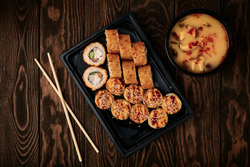 Tray of baked rolls and Tom Yum soup on wooden table, oriental cuisine