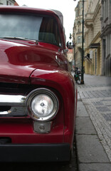 Fototapeta premium Red retro car parked on a paved European street close-up