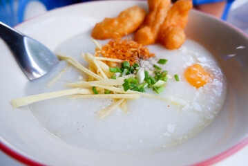 Rice porridge with egg, Ginger, onion, deep-fried dough sticks in bowl. Popular breakfast concept.