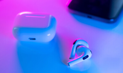 White modern headphones wireless earphones with case, neon pink and blue background