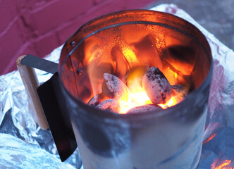 Charcoal chimney starter with glowing hot coals.