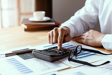 Fototapeta premium Banking and savings finance concept, close-up of businessman's hands pressing a calculator. and fill out the documents for tax refund and tax savings