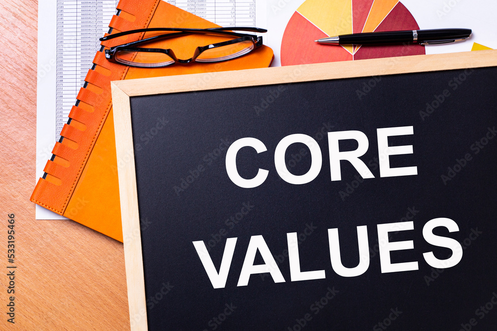 Poster on the office table is an orange notepad, black glasses, a pen and a note-board with the text core v