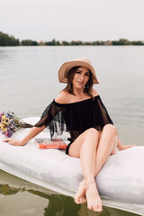 Young sexy girl in a swimsuit on a water mattress on the lake