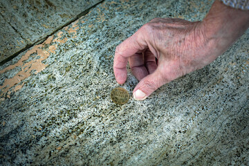 close-up of old womans hand picking up a coin from the floor