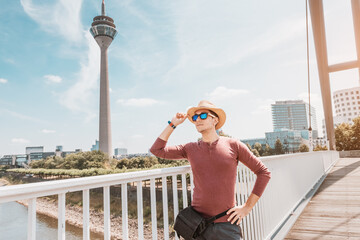 A young happy man at the Media Harbor admiring view of TV-tower in Dusseldorf. Travel abroad and...