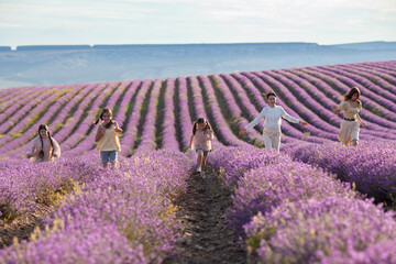 Portrait of a mother with her daughters on a background of lavender. Cheerful family runs through the lavender field.