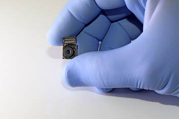 Scientist's hand with a blue glove holding the camera of a mobile phone
