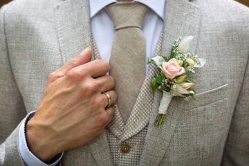 Bräutigam im Anzug mit Ansteckblumen und Ehering