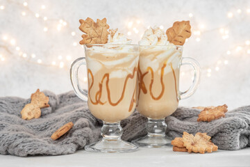 Pumpkin spice latte in a glass mug with caramel and cinnamon cookies with Autumn decoration